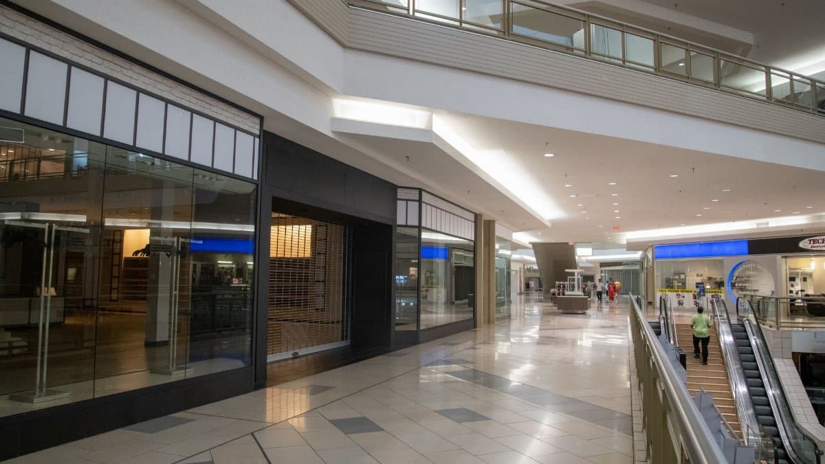 Spacious and contemporary mall interior with closed stores and escalator.