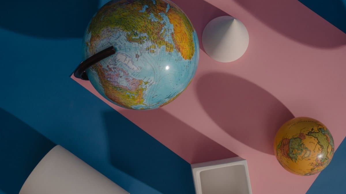 Artistic flat lay of globes and geometric shapes on colorful background.