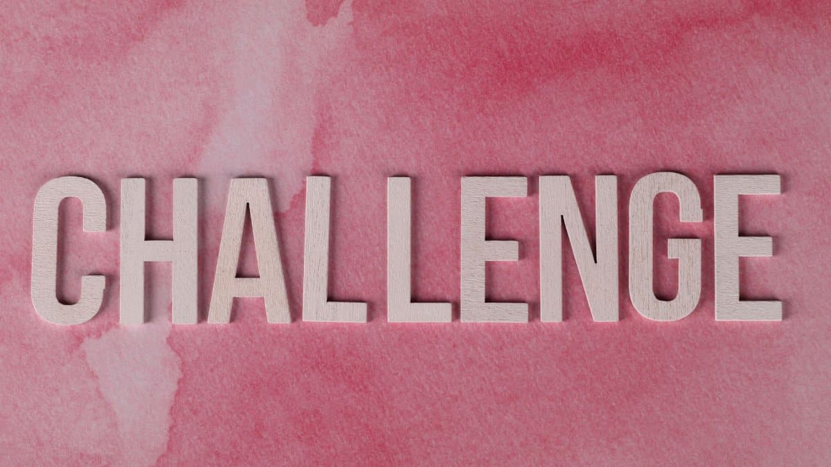 Text 'CHALLENGE' in bold on textured pink watercolor background for motivation.
