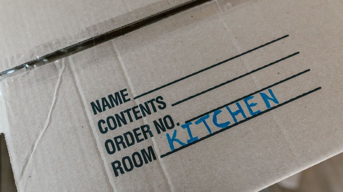 Cardboard box labeled with room destination for kitchen during moving process.