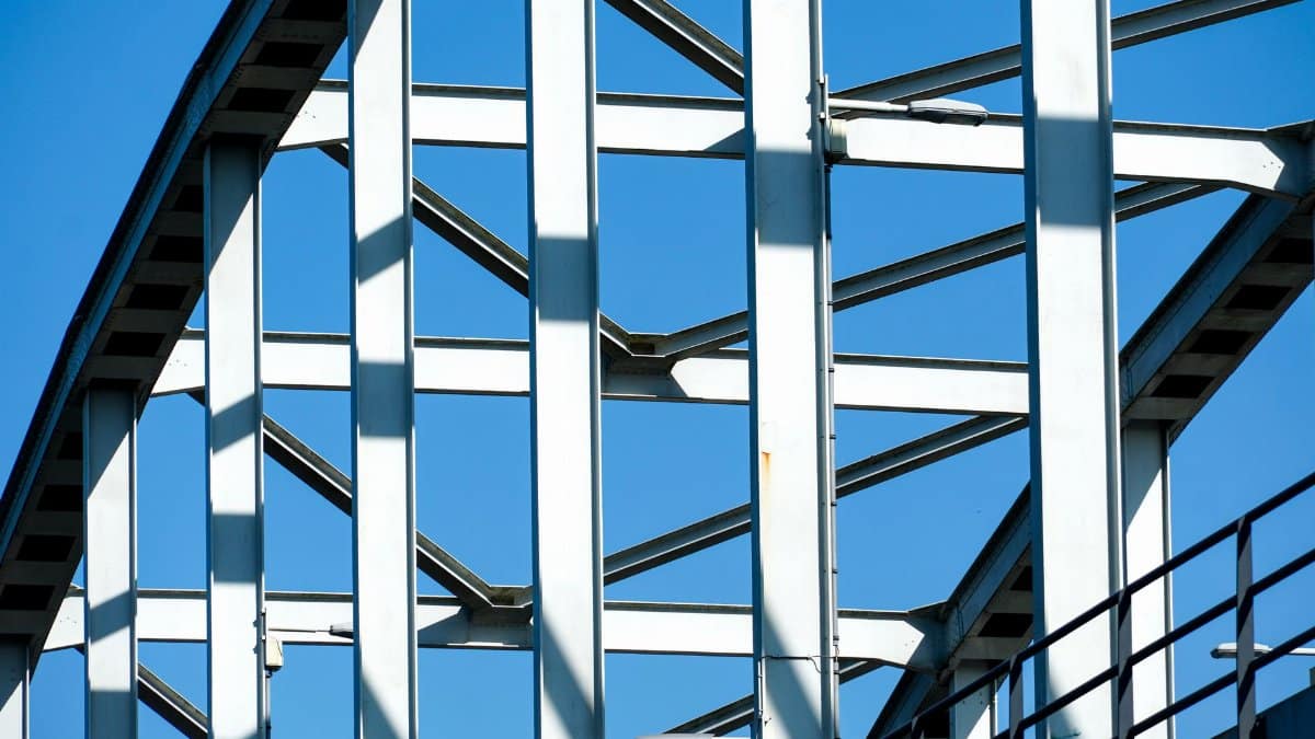 Close-up of a steel bridge's geometric framework against a clear blue sky, showcasing modern architecture.