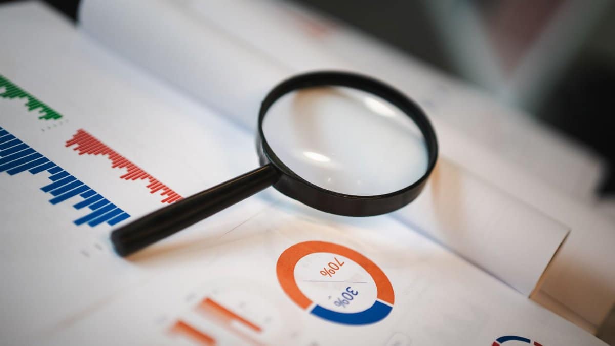 An image showcasing a magnifying glass placed on financial graphs and charts depicting statistical data.