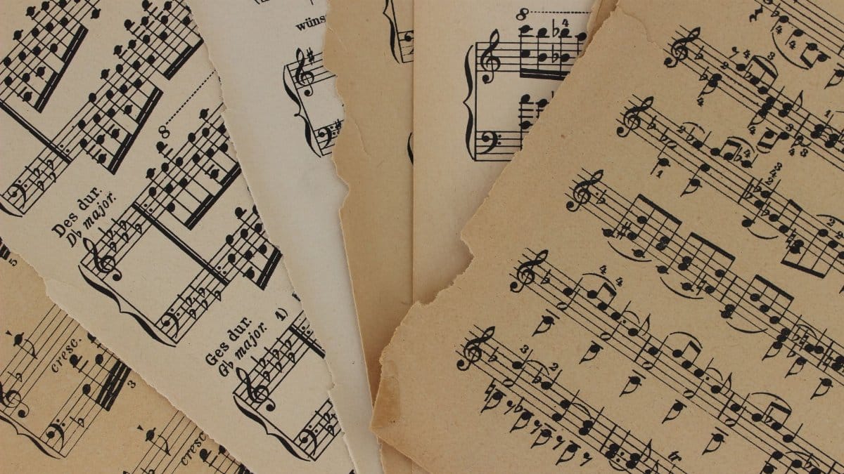 Close-up of vintage sheet music with torn edges, highlighting musical notations and history.