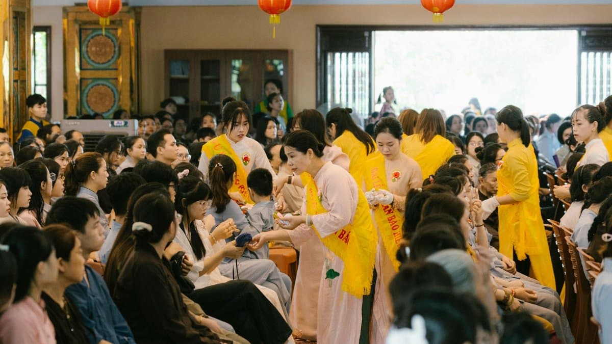 A large indoor cultural ceremony with people in traditional attire, engaging in ritual activities.