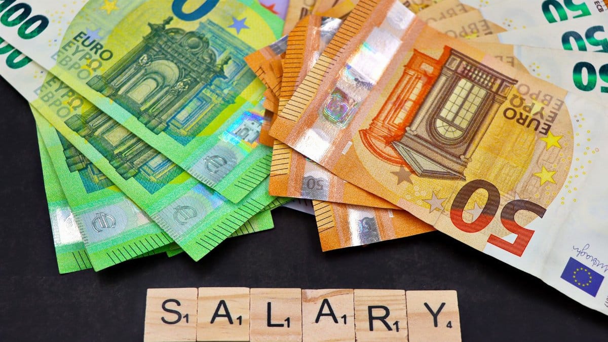 Euro banknotes alongside wooden Scrabble letters spelling 'salary' symbolize financial earnings and payroll.