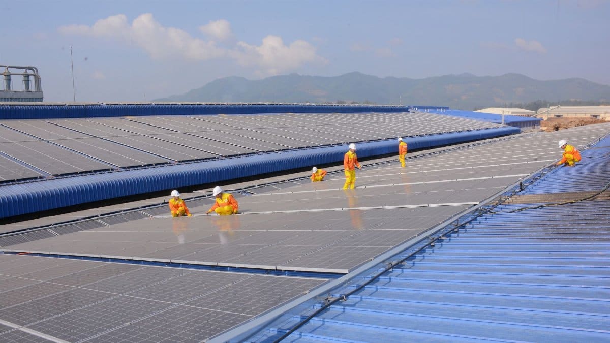 Workers installing solar panels on a large roof, highlighting renewable energy and sustainability.