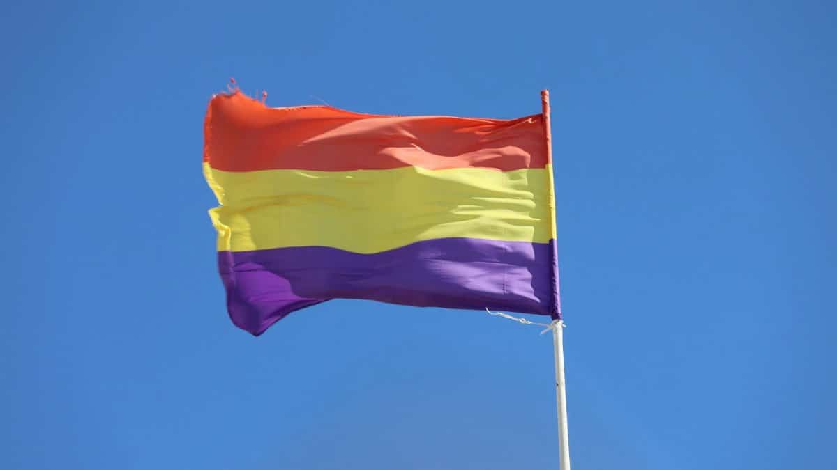 The Spanish Republican flag waves under a bright blue sky in El Puerto de Santa María, Spain.