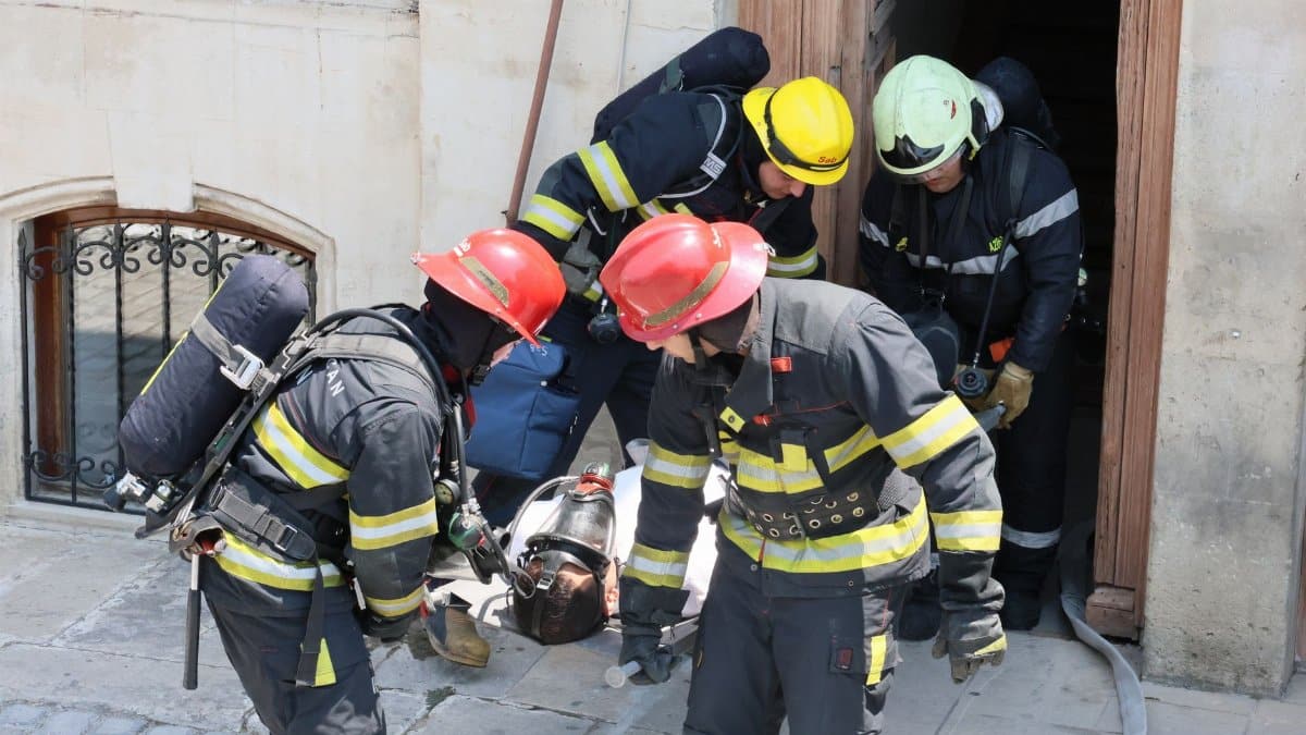 Firefighters executing rescue operations during a training drill outdoors.