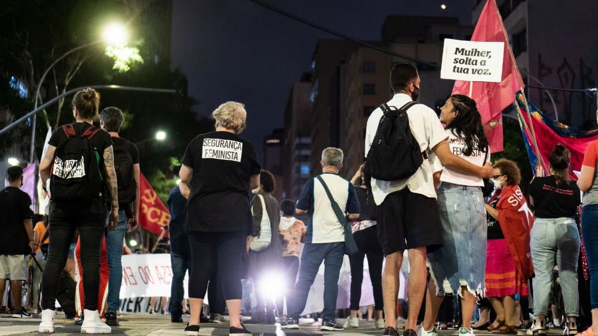 A group of people gathered during a nighttime feminist protest on a city street.