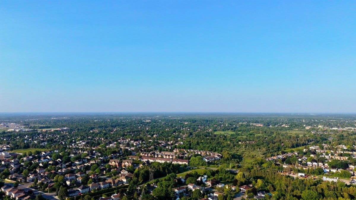 Aerial view of a suburban neighborhood with lush green vegetation under a clear blue sky.