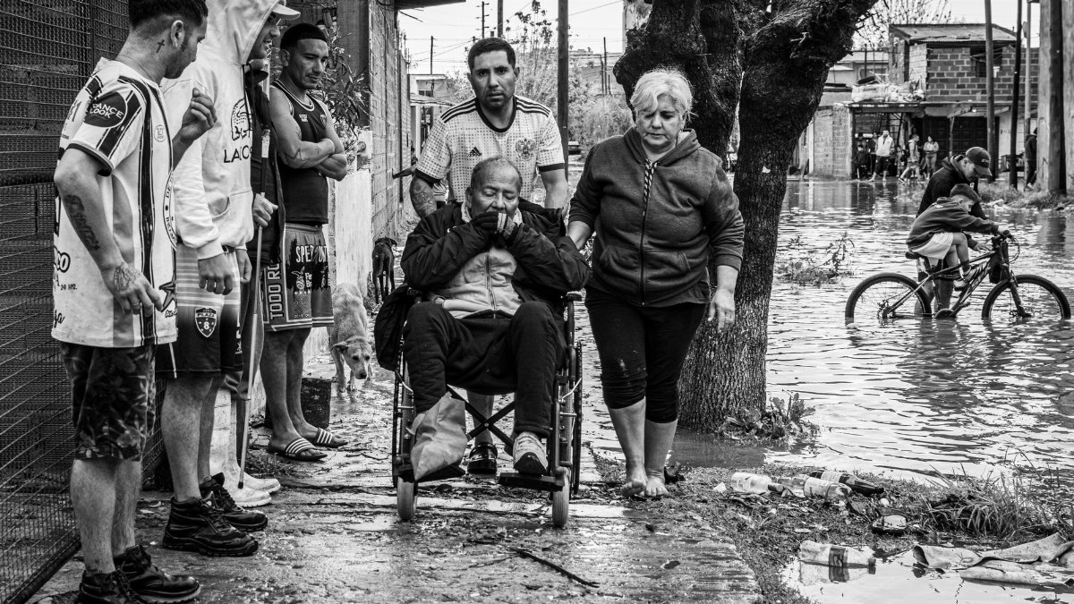 Residents assist an elderly man in a wheelchair through flooded streets in Buenos Aires, Argentina.