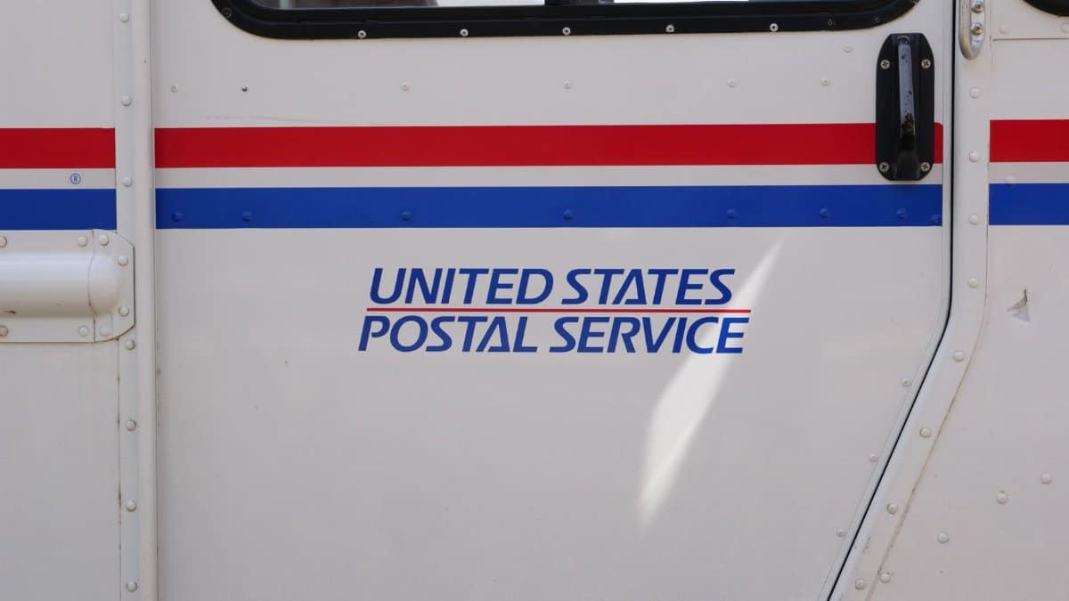 Side panel view of a United States Postal Service mail truck emphasizing its logo.