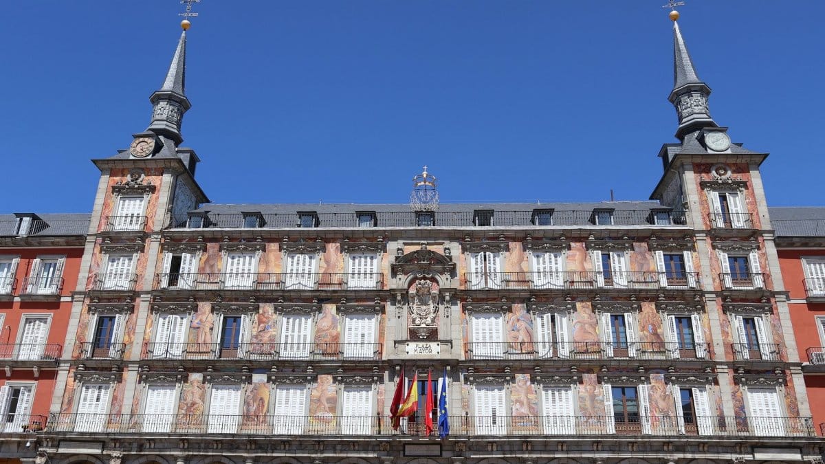 Historic Casa de la Panadería with flags at Plaza Mayor, Madrid, on a sunny day.