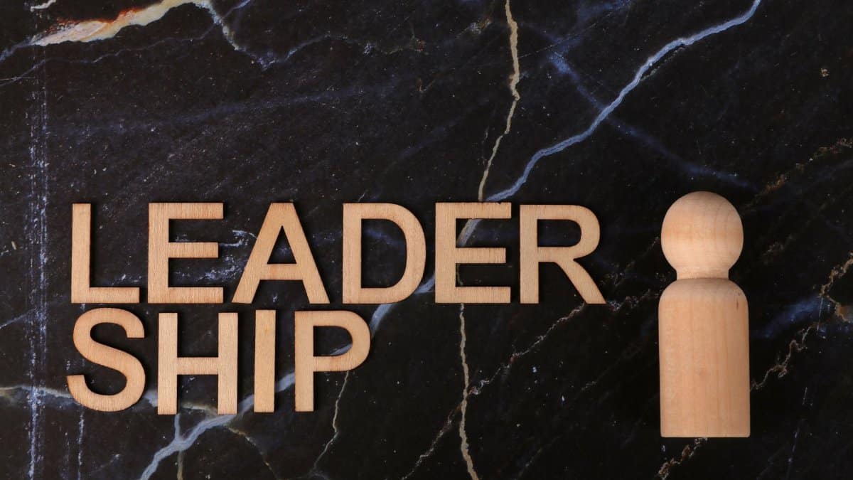 Wooden leadership text and figurine on marble representing management concepts.