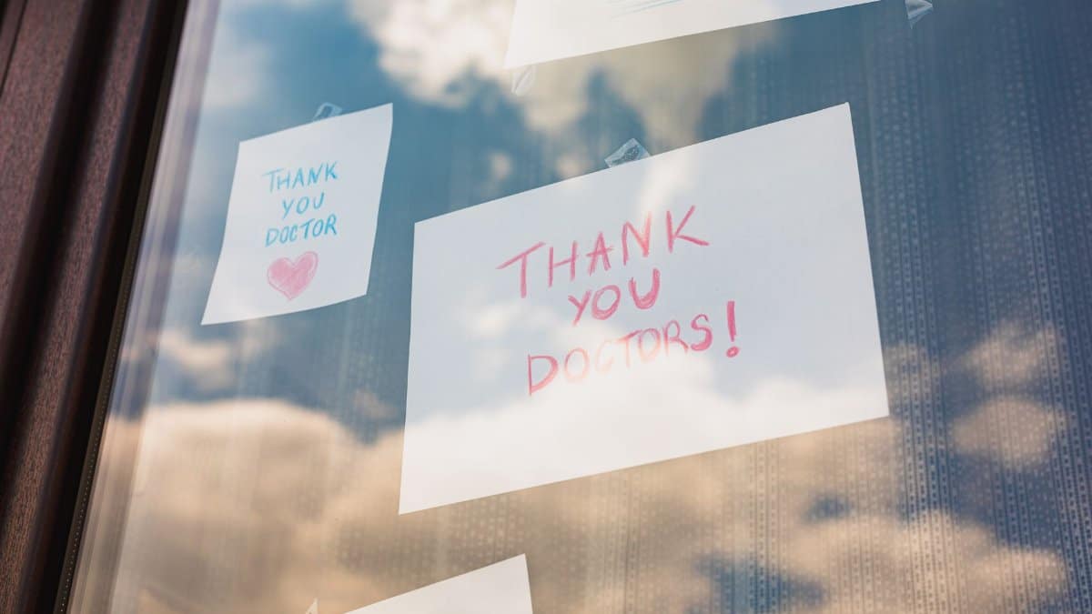 Handwritten thank you notes to doctors taped on a window, reflecting gratitude in challenging times.