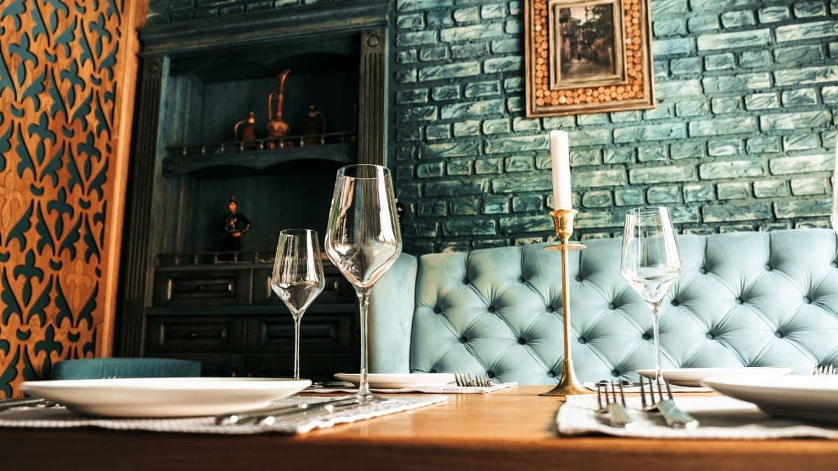 A stylish restaurant setting with blue brick walls, elegant table settings, and sophisticated decor.