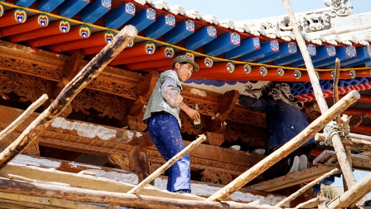 Skilled artisans restore intricate wooden details on a Chinese temple roof.
