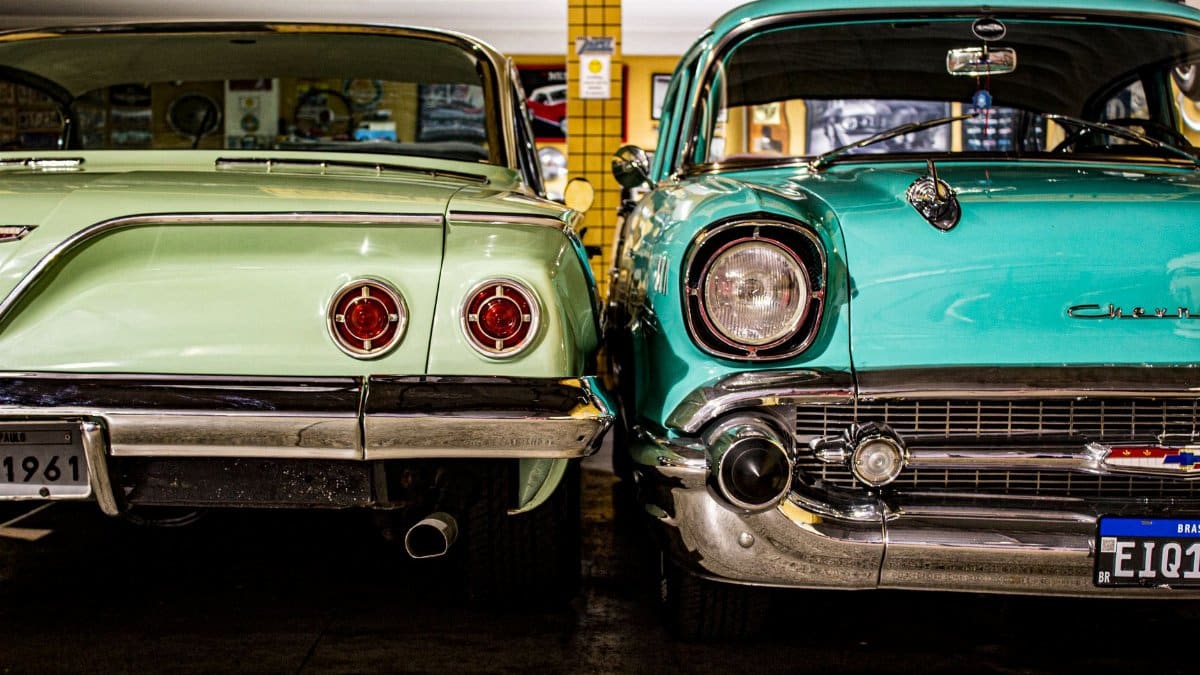Two vintage Chevrolet cars parked in a retro garage, showcasing their classic design and chrome details.