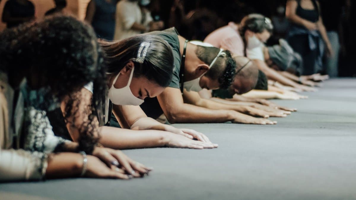 A group of adults wearing face masks in prayer, demonstrating faith and worship indoors.