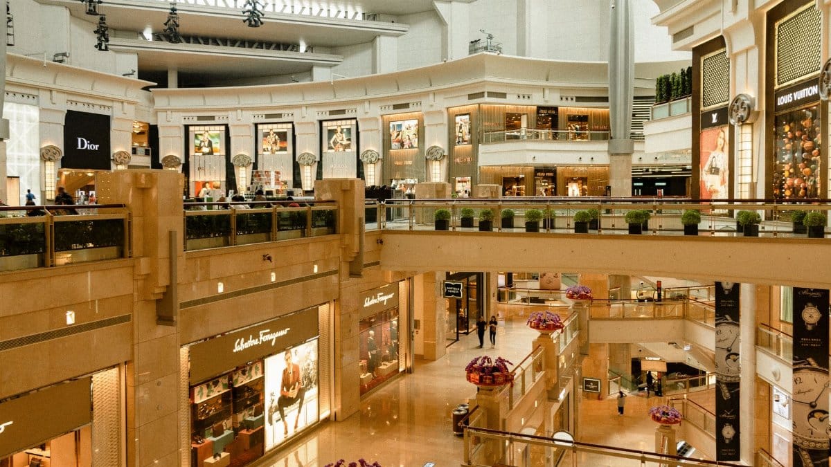 Contemporary design of big mall interior with ribbed column and decorative elements on ceiling with glowing corridors illuminated by artificial lights and signboards with inscriptions