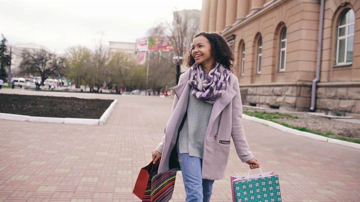 Happy woman carrying shopping bags in an outdoor city area.