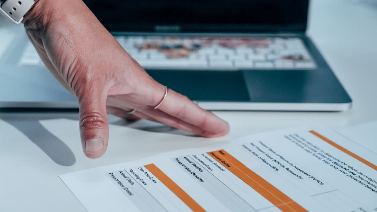 Close-up of a hand reviewing a financial report on a laptop, indicating focus on business analysis.