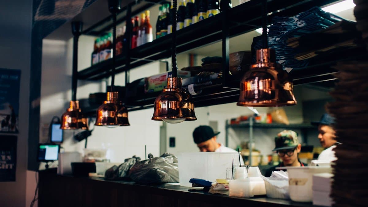 Contemporary restaurant kitchen with staff preparing food under warm lighting.