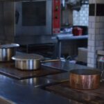 Stainless steel pots on a kitchen counter in a professional restaurant setting.