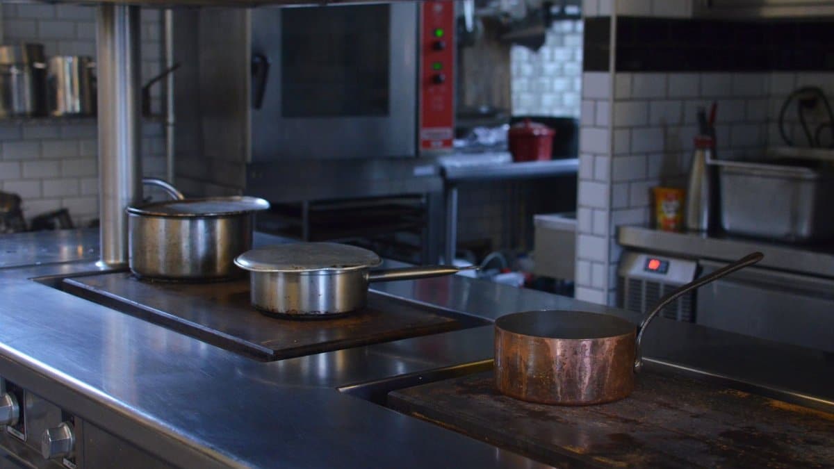 Stainless steel pots on a kitchen counter in a professional restaurant setting.