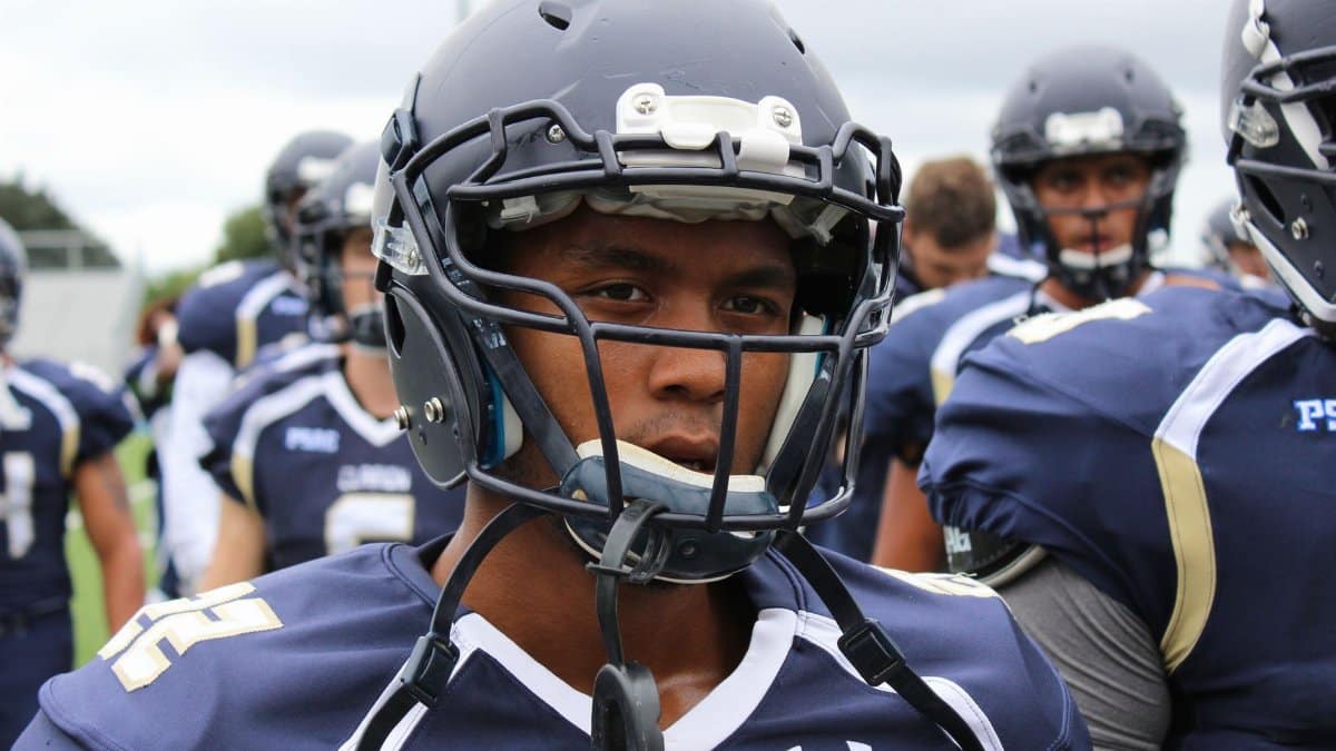 Close-up of a football player in helmet and uniform, ready for the game on a cloudy day.