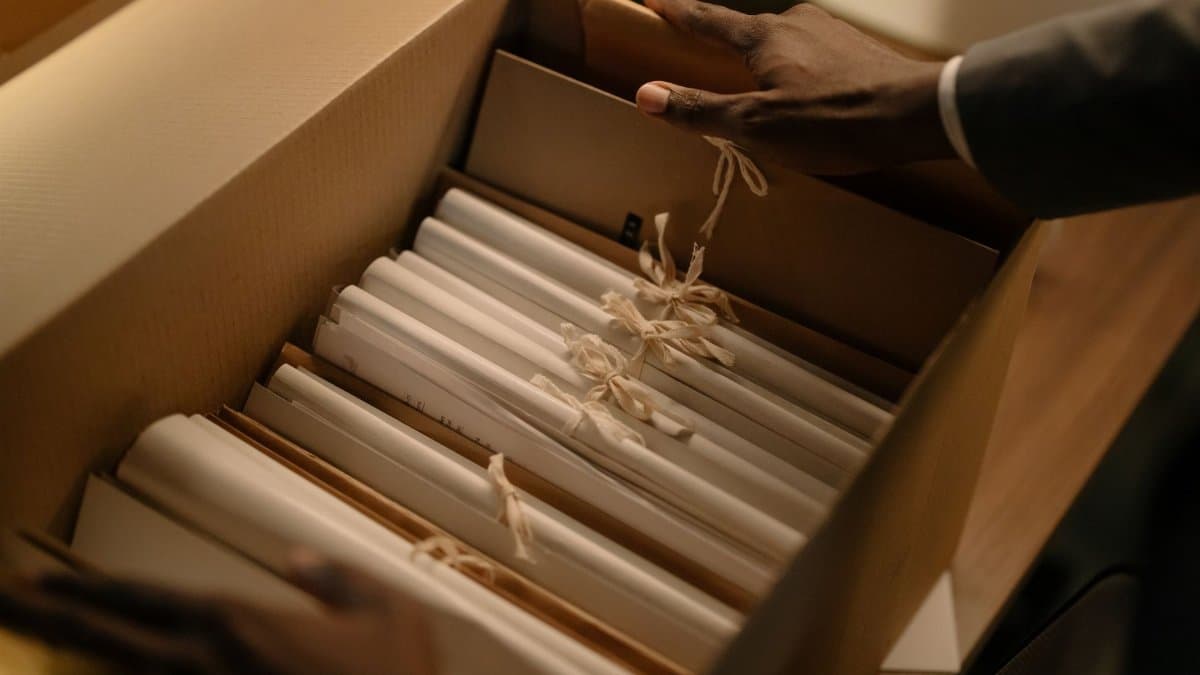 Hands organizing files in a box, symbolizing investigation and research.