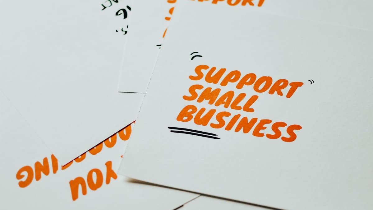 Close-up of motivational cards promoting support for small business on white background.