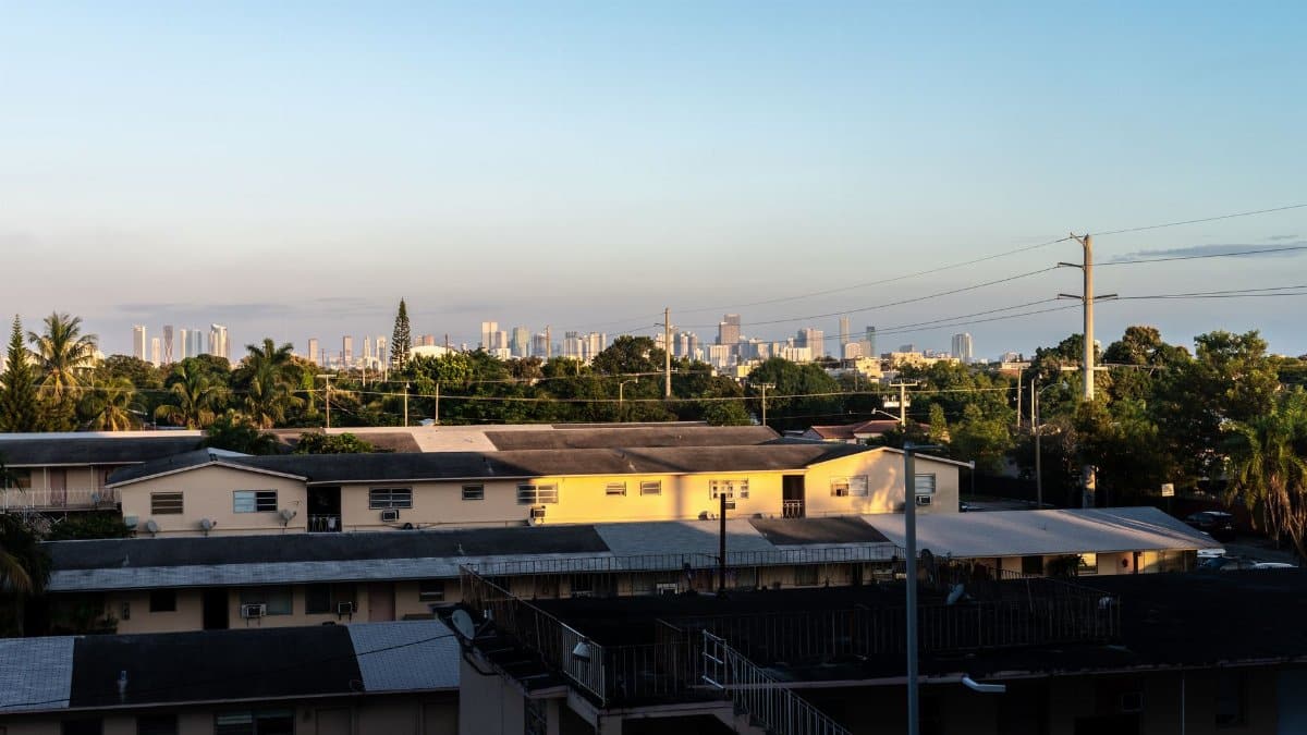 View of Miami skyline from Coral Gables at sunset with residential buildings in foreground.
