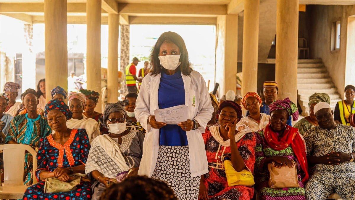 A female doctor giving a health lecture to a group of senior women indoors.