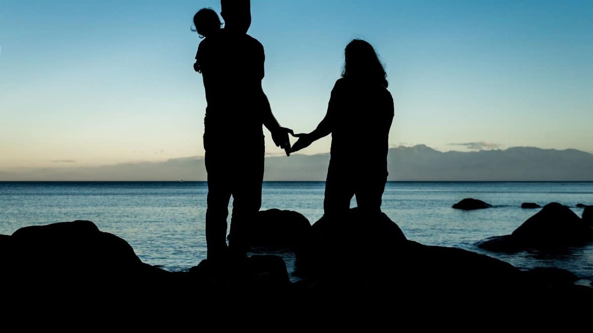 A family silhouette enjoys the serene sunset at Metchosin Beach, Canada.