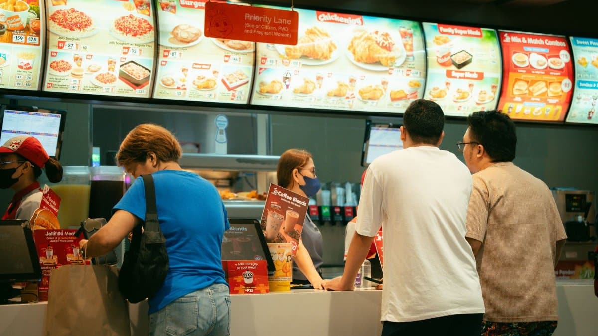 Customers ordering food at a fast food restaurant counter. Busy atmosphere.