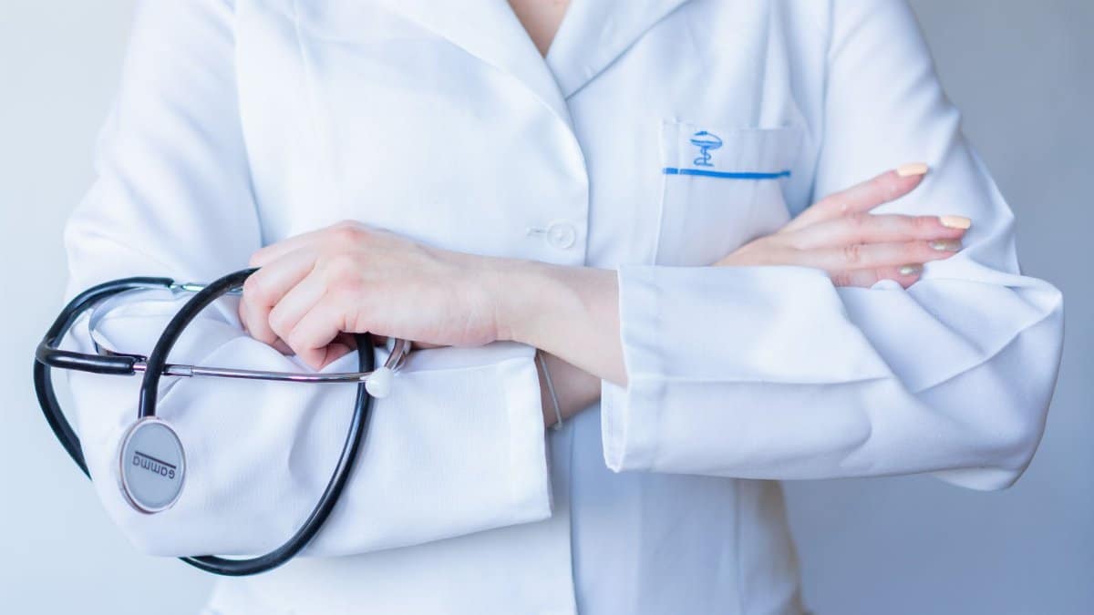 A close-up image of a doctor in a white coat with a stethoscope and arms crossed.