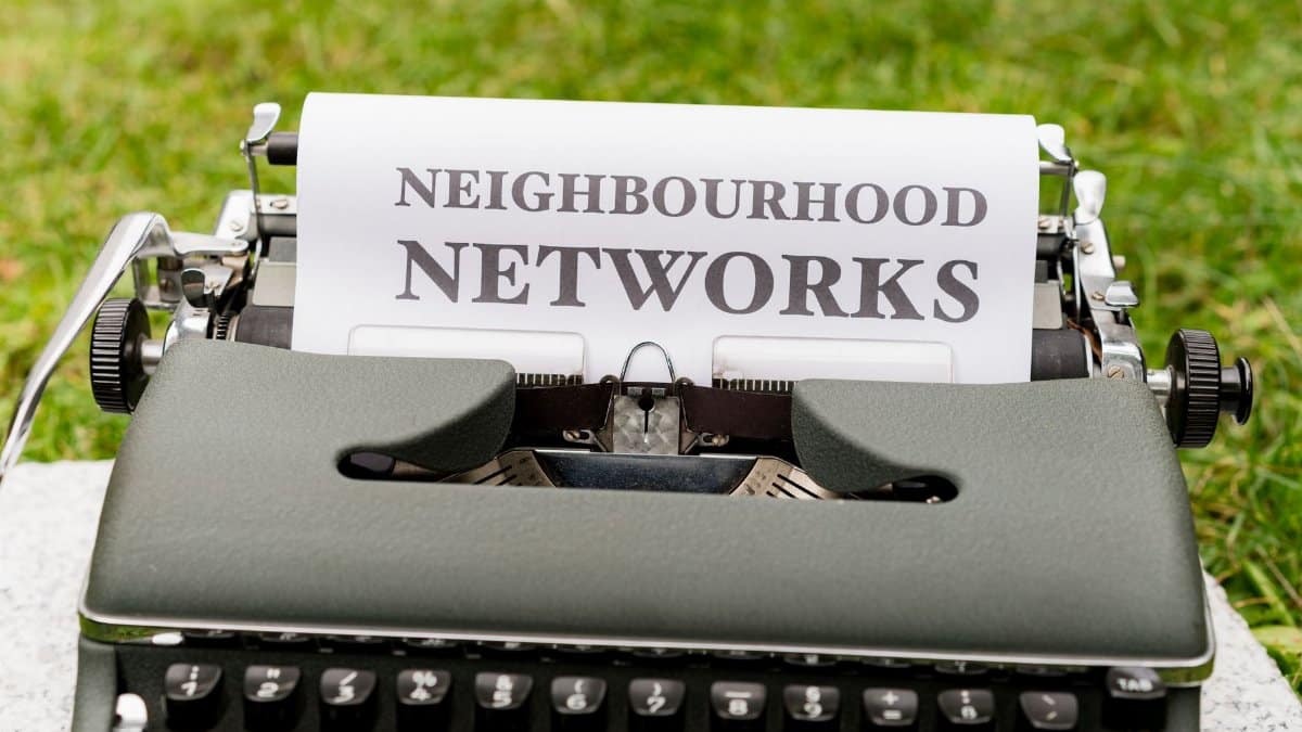 Retro typewriter displaying 'Neighborhood Networks' on paper, outdoors.