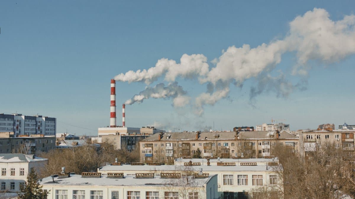 Cityscape with smoking chimneys and clear sky, depicting industry.