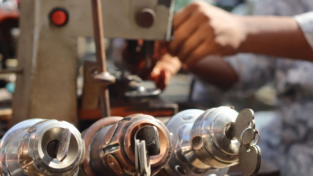 Close-up image of locksmith tools and hands working with a key machine outdoors.