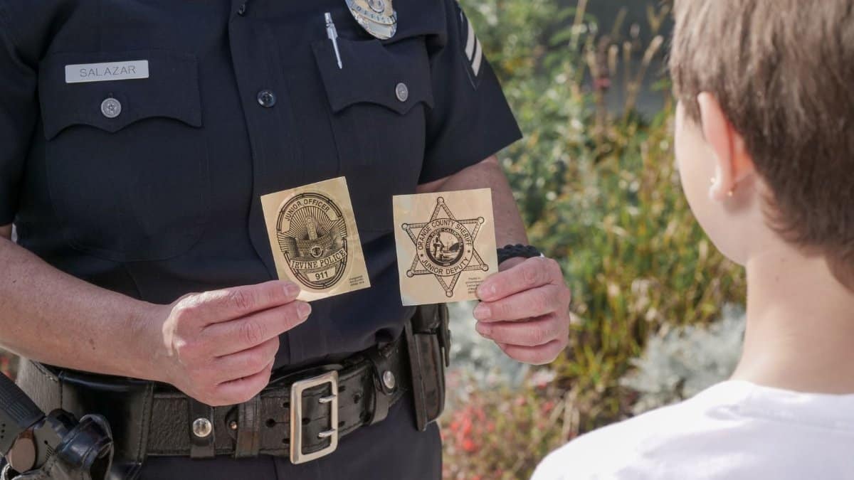 Officer showing law enforcement badges to a child outdoors, fostering positive interaction.