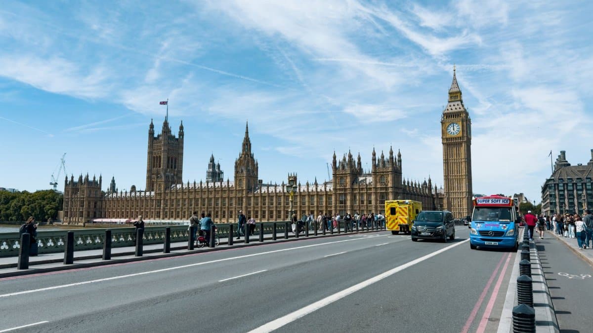 Iconic view of Big Ben and Westminster Bridge bustling with tourists and traffic on a sunny day in London.