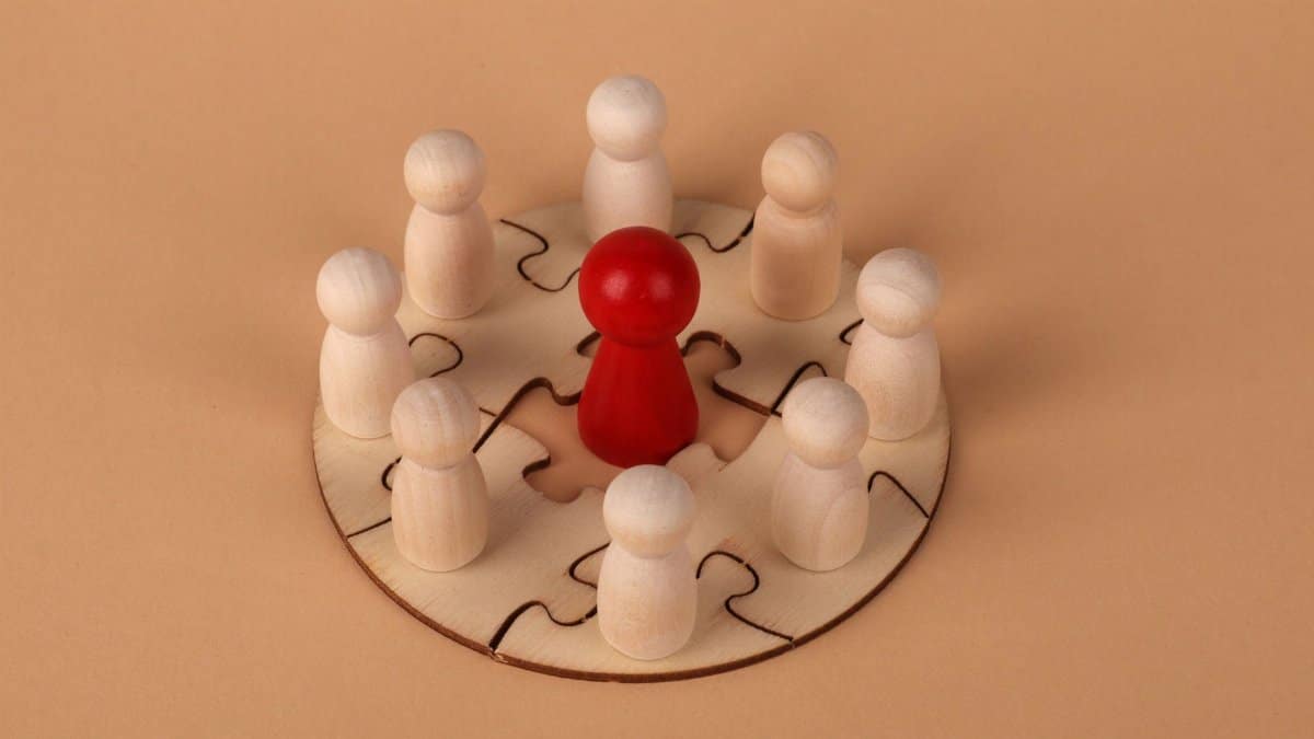 Wooden peg figures on a puzzle board representing teamwork and leadership concepts.