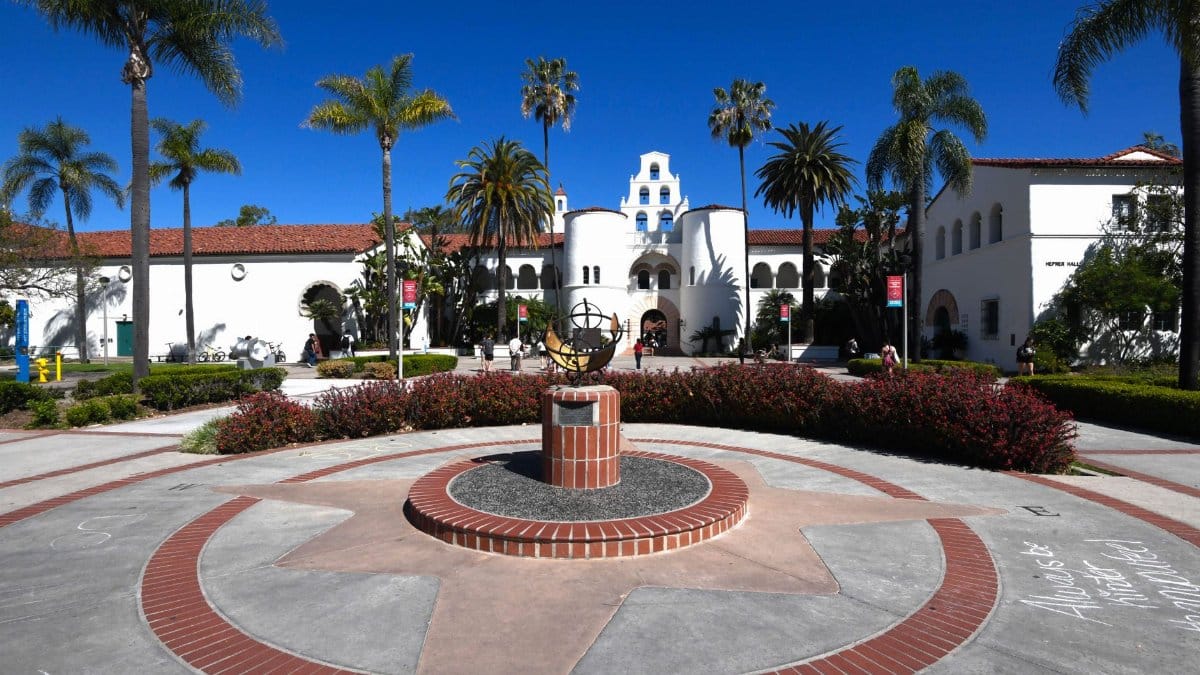 Sunny day at a historic university with palm trees and compass in the courtyard.