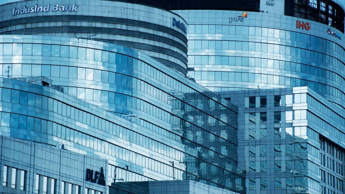 A contemporary glass skyscraper showcasing sleek architecture and corporate logos in an urban setting.