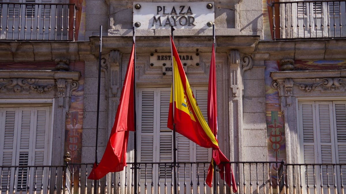Detailed view of Plaza Mayor's facade with flags in Madrid, Spain, highlighting classic architecture.