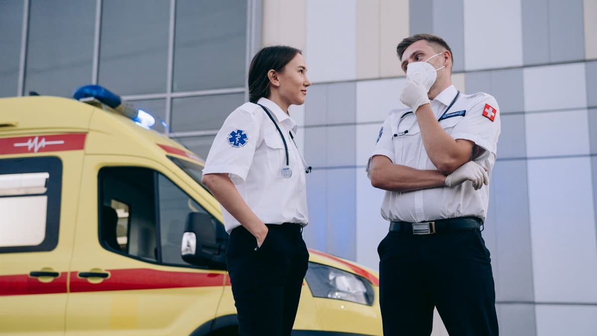 Paramedics conversing outdoors near an ambulance, highlighting teamwork in emergency medical services.