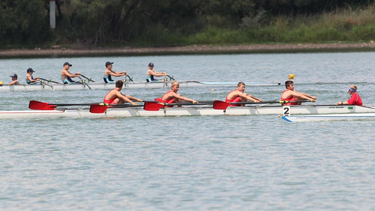 Multiple rowing teams competing in a dynamic team sport race on a river.
