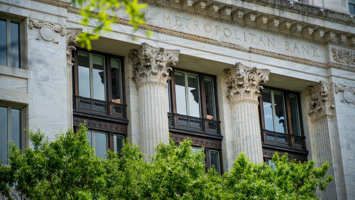 Close-up of the neoclassical columns and facade of Metropolitan Bank surrounded by greenery.