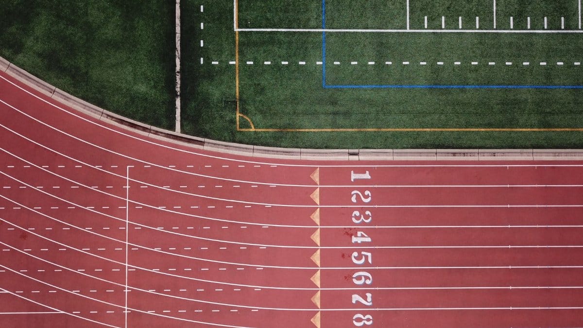 Aerial perspective of a red running track and adjacent green field.